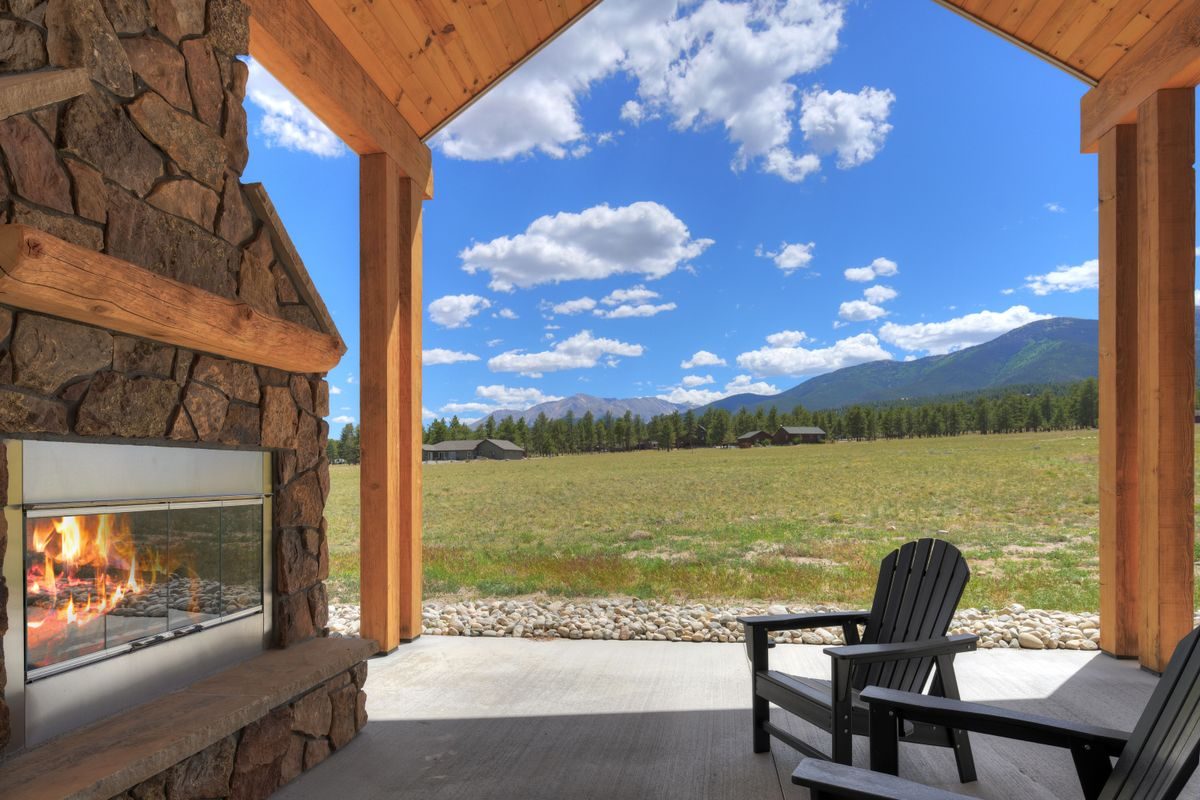 Covered patio with a stone fireplace framing the Collegiate Peaks